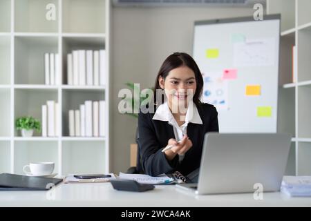 Beautiful asian businesswoman woman using calculator and laptop for doing finance on an office desk, tax, report, accounting, statistics, and analysis Stock Photo
