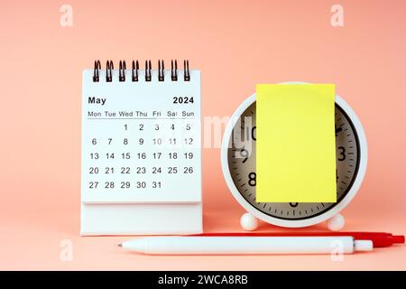 May 2024 desk calendar With Adhesive Note on Alarm Clock Stock Photo