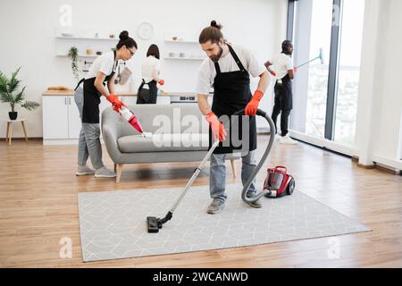 Professional bearded cleaner from cleaning service vacuums carpet Stock Photo