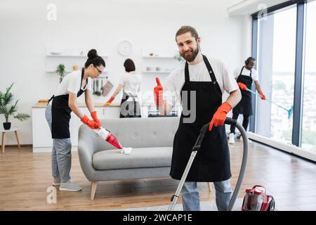 Portrait of professional bearded cleaner from cleaning service vacuums carpet. Stock Photo
