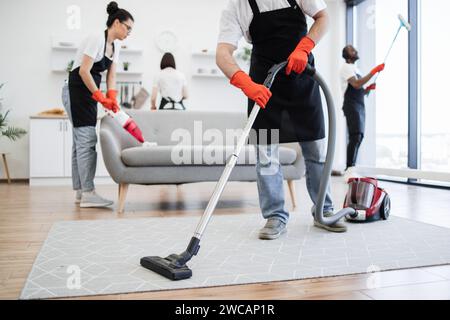 Cropped view of professional cleaner from cleaning service vacuums carpet. Stock Photo