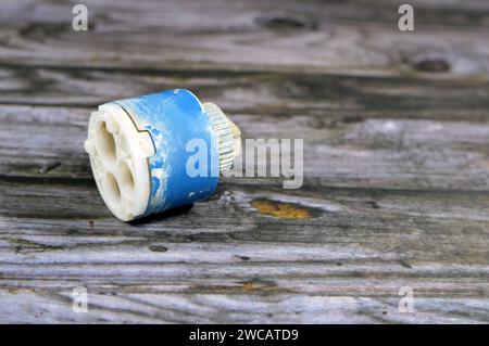 A used broken shower faucet tap body cartridge parts of plastic that needs to be fixed or replaced for water leakage, plumbing and maintenance concept Stock Photo