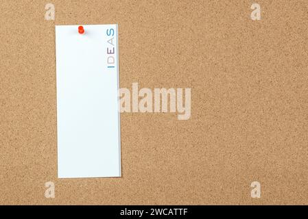 Blank notice with the word ideas printed in vertical on it on a cork board. Copy space. Stock Photo