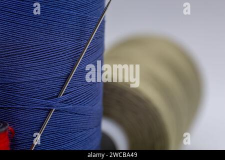 An image showcasing two spools of thread, one in a neutral color and the other in a vibrant shade of blue, positioned side by side Stock Photo