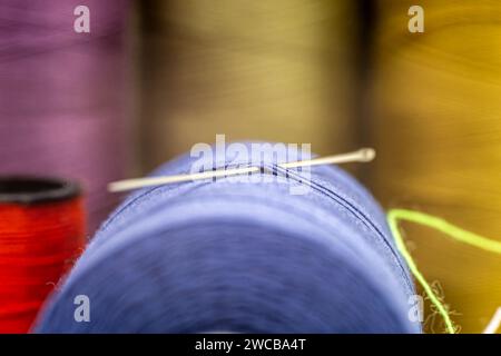 A closeup of a needle in a thread with other colorful needles in the blurry background Stock Photo