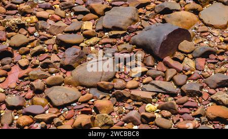 Pink stone texture and background. Close up of wet decorative stones. The Pink Coast or Lan Him Chomphu with sea background at Chanthaburi in Thailand Stock Photo
