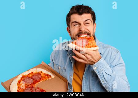 Funny Man Eating Pizza Standing Holding Box Over Blue Background Stock Photo