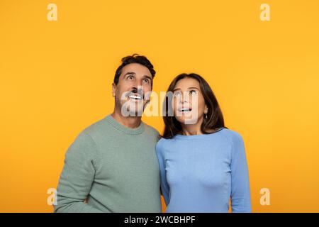 An intrigued couple looks upwards with a sense of wonder, the woman leaning on the man Stock Photo