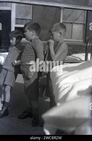 1942, historical, wartime and three patients, young boys, outside by their metal beds at Queen Mary's Hospital Childrens hospital, Carshalton, Surrey, England, UK, one boy has his hand in plaster. Stock Photo