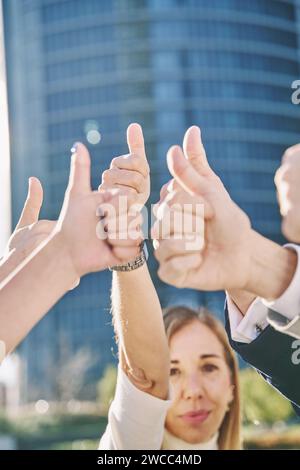 group of business people with their hands up and thumbs up. vertical photograph, selective focus on hands, mature woman out of focus. Closeup of corpo Stock Photo