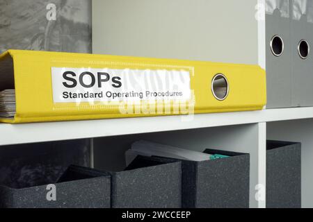 SOP Standard operating procedure concept. A yellow folder lies on an office shelf. Stock Photo