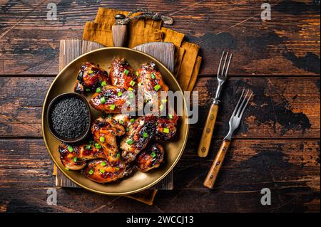 Teriyaki chicken wings with black sesame in a plate. Wooden background. Top view. Stock Photo