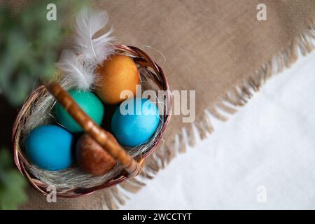Multi coloured Easter eggs in wicker basket on rustic background Stock Photo
