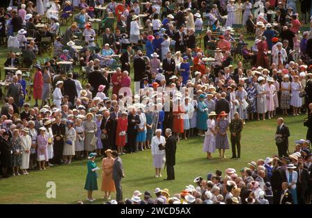 Queen Elizabeth II Buckingham Palace garden party. The Queen in green dress (bottom left) and wearing white long gloves, meeting greeting people who have been nominated to meet her and attend one of her summer garden parties. London, England June 1985. 1980s UK HOMER SYKES Stock Photo