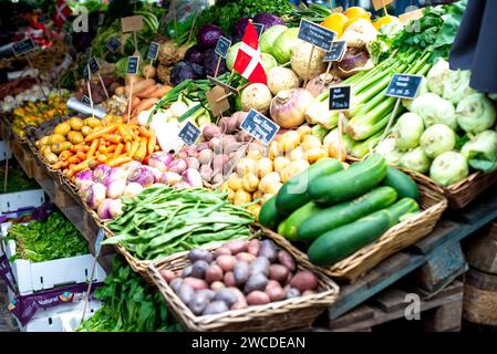 A vibrant assortment of assorted fresh fruits and vegetables, neatly arranged in rustic baskets, are prominently showcased in a bustling market Stock Photo