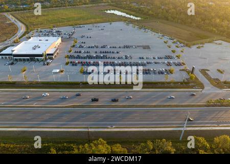 View from above of dealers outdoor parking lot with many brand new cars in stock for sale on highway side. Concept of development of american Stock Photo
