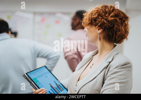 Young professionals collaborate and brainstorm ideas for business success in a corporate office, using sticky notes and glass walls. Stock Photo