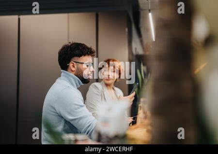 Colleagues discussing market analysis, strategizing, and enjoying tea in a pleasant office kitchen. Multiracial team, successful start-up, teamwork. Stock Photo