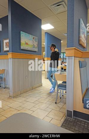 Gen Z young man talking on telephone inside a Culver's Restaurant - November 2023 Stock Photo