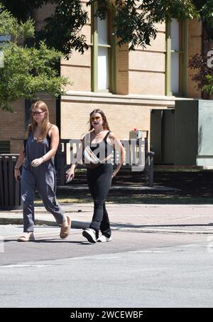 Two pregnant Gen Z women crossing a street in downtown Georgetown Texas - August 2023 Stock Photo