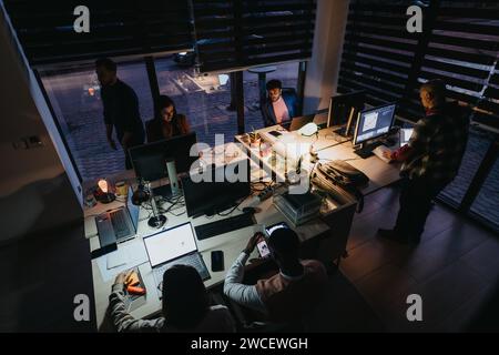 Diverse business team working late into the night, collaborating and strategizing for success. Stock Photo