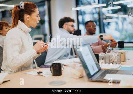 Diverse business team collaborates in an office, reviewing documents and analyzing market data for growth. Stock Photo