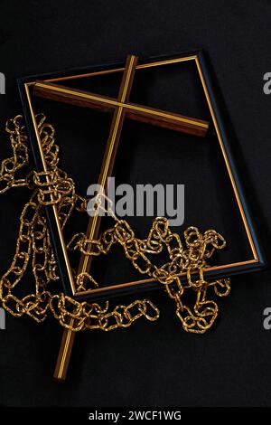 Display on black shows picture frame with Christian cross &  gold chains representing the cross of salvation and the broken chains of sin & bondage. Stock Photo