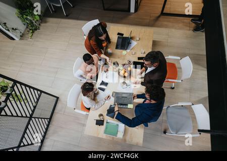 A diverse group of professionals collaboratively discussing business strategies and analyzing market data in a creative office environment. Stock Photo