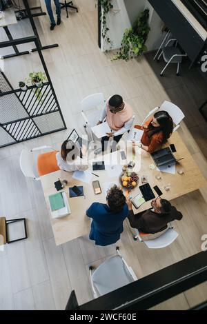 Multiethnic colleagues in a creative office discussing business expansion, doing paperwork, and working together on a project. Stock Photo