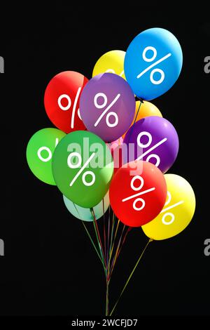 Discount offer. Bunch of balloons with percent signs against black background Stock Photo