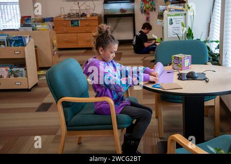 Kansas City, Kansas. Nine year old bi-racial girl working with construction paper in the F. L. Schlagle Library and Environmental Learning Center. It Stock Photo
