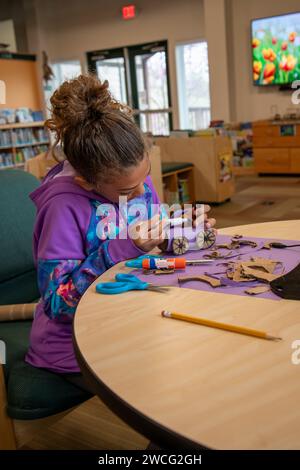 Kansas City, Kansas. Nine year old bi-racial girl making a car  with construction paper in the F. L. Schlagle Library and Environmental Learning Cente Stock Photo