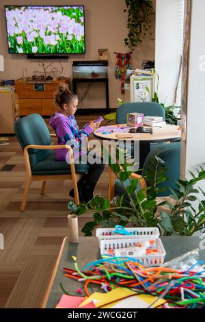 Kansas City, Kansas. Nine year old bi-racial girl working with construction paper in the F. L. Schlagle Library and Environmental Learning Center. It Stock Photo