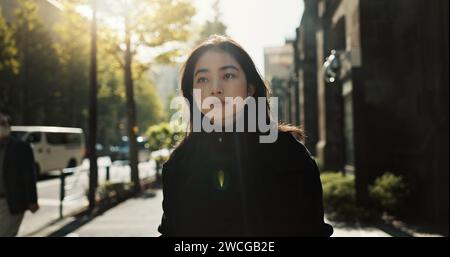 Walking, trees and Japanese woman in the city for tourist sightseeing in the street on weekend trip. Serious, adventure and young female person Stock Photo