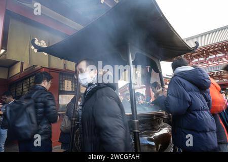Tokyo, Japan. January 2024. Faithful at the  incense burner in front of the Sensō-ji temple in the city center. Stock Photo