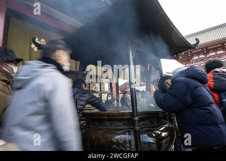 Tokyo, Japan. January 2024. Faithful at the  incense burner in front of the Sensō-ji temple in the city center. Stock Photo