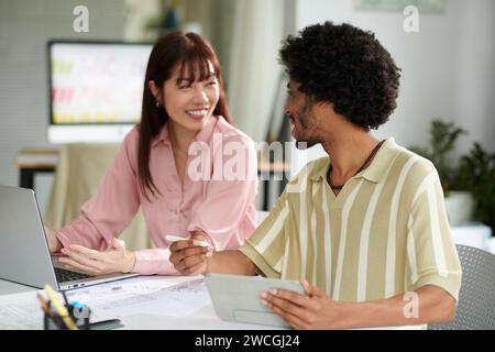 Cheerful coworkers discussing new ideas when working on mobile app development Stock Photo