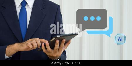 A man wearing a suit typing on tablet computer, live chat chatting with AI. Social network concepts, chatting conversation in chat box icons pop up. A Stock Photo