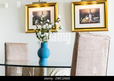a glass dining table surrounded by artwork in luxury mediterranean apartment Stock Photo