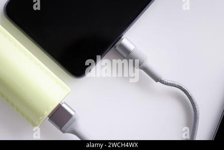 Mobile phone is connected with cable to power bank closeup Stock Photo