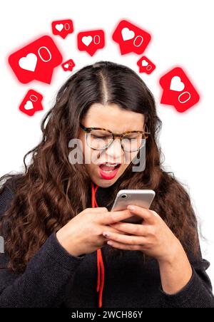 Concept of inactivity in social networks. Girl looks in surprise at her phone on a white background. Social media addiction. Red glowing like icons. Stock Photo