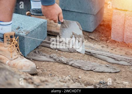 Bricklayer laying high-density footing concrete blocks Stock Photo
