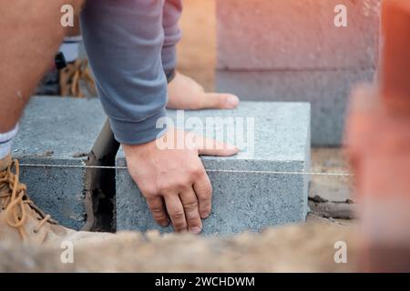 Bricklayer laying high-density footing concrete blocks Stock Photo