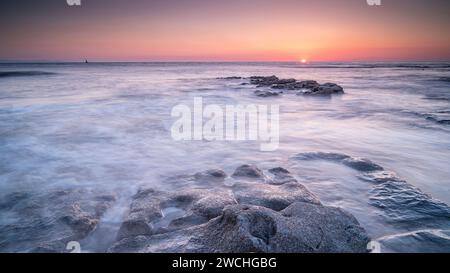 Rocky shoreline at Nash Point, Glamorgan, south Wales. Sunset over the shoreline, long exposure to smooth out the movement in the sea. Stock Photo
