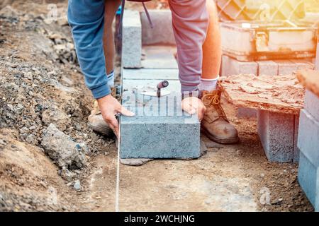 Bricklayer laying high-density footing concrete blocks Stock Photo