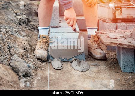 Bricklayer laying high-density footing concrete blocks Stock Photo
