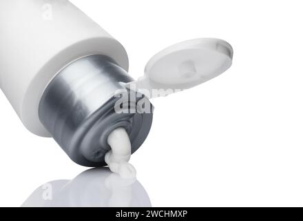 White tube with a gray cap for cream or cosmetics on a white background. Squeezed cream from a tube. Stock Photo