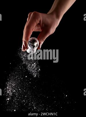 Female hand with red manicure pours glitter on black background Stock Photo