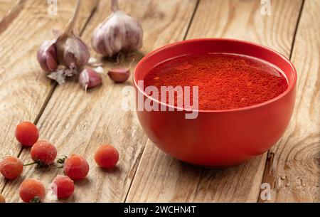 Tomato soup on a wooden table with cherry tomatoes and heads of garlic. Stock Photo