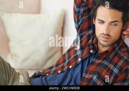 Relax, thinking and man on sofa in home for afternoon nap, resting and calm in living room. Tired, thoughtful and person on couch lying for dreaming Stock Photo
